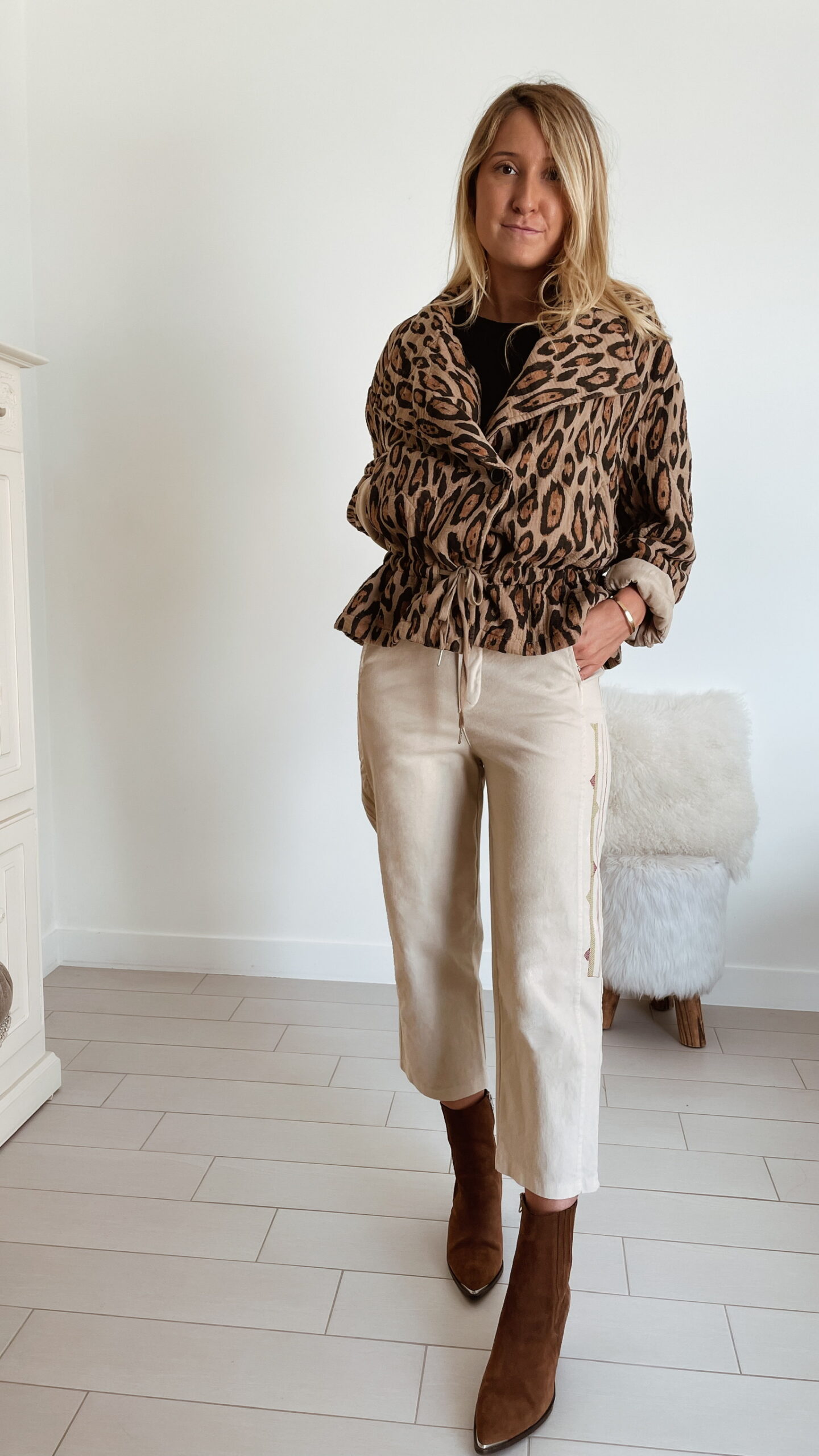 Femme portant une veste perfecto léopard Mac de Sozély, assortie à un pantalon beige et des bottines marron, look chic et tendance pour l’automne.