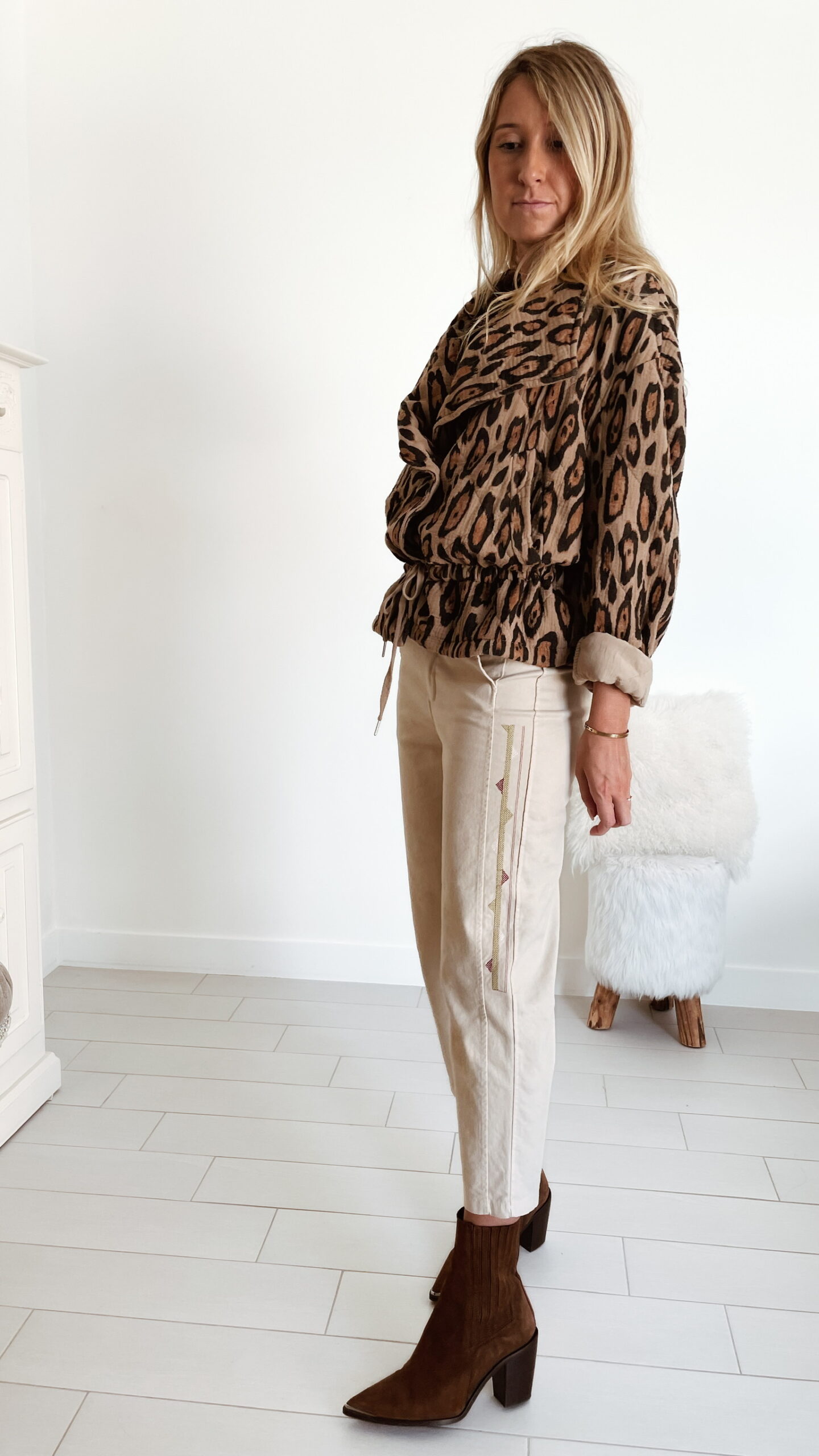 Femme portant une veste perfecto léopard Mac de Sozély, assortie à un pantalon beige et des bottines marron, look chic et tendance pour l’automne.