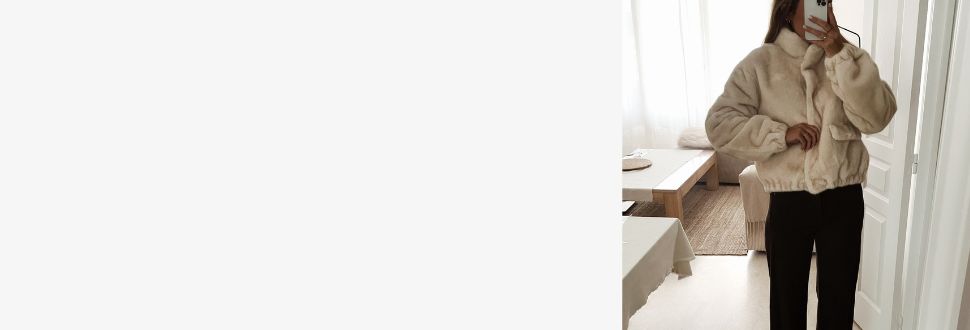 Femme portant une veste courte en fausse fourrure beige, associée à un pantalon noir fluide. Le look est élégant et chaleureux, parfait pour l’hiver.