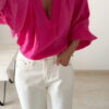 Blouse rose fuchsia fluide portée avec un jean blanc taille haute et bijoux dorés
