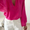 Blouse rose fuchsia fluide portée avec un jean blanc taille haute et bijoux dorés