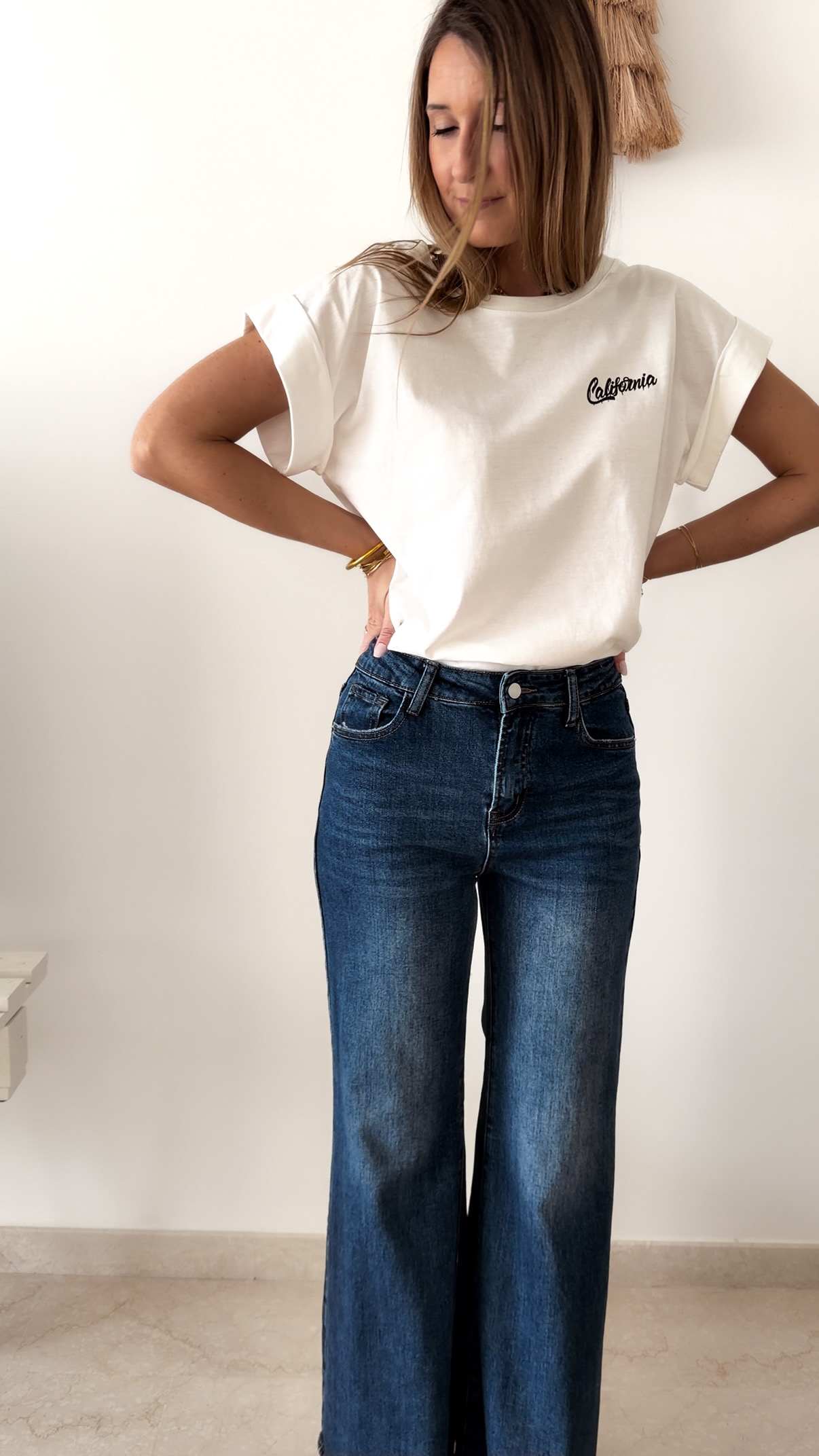 T-shirt blanc à manches retroussées avec imprimé palmier « Santa Barbara California » au dos, porté avec un jean large taille haute.