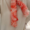 Foulard rose et orange motif Toile de Jouy porté avec pull beige et pantalon blanc