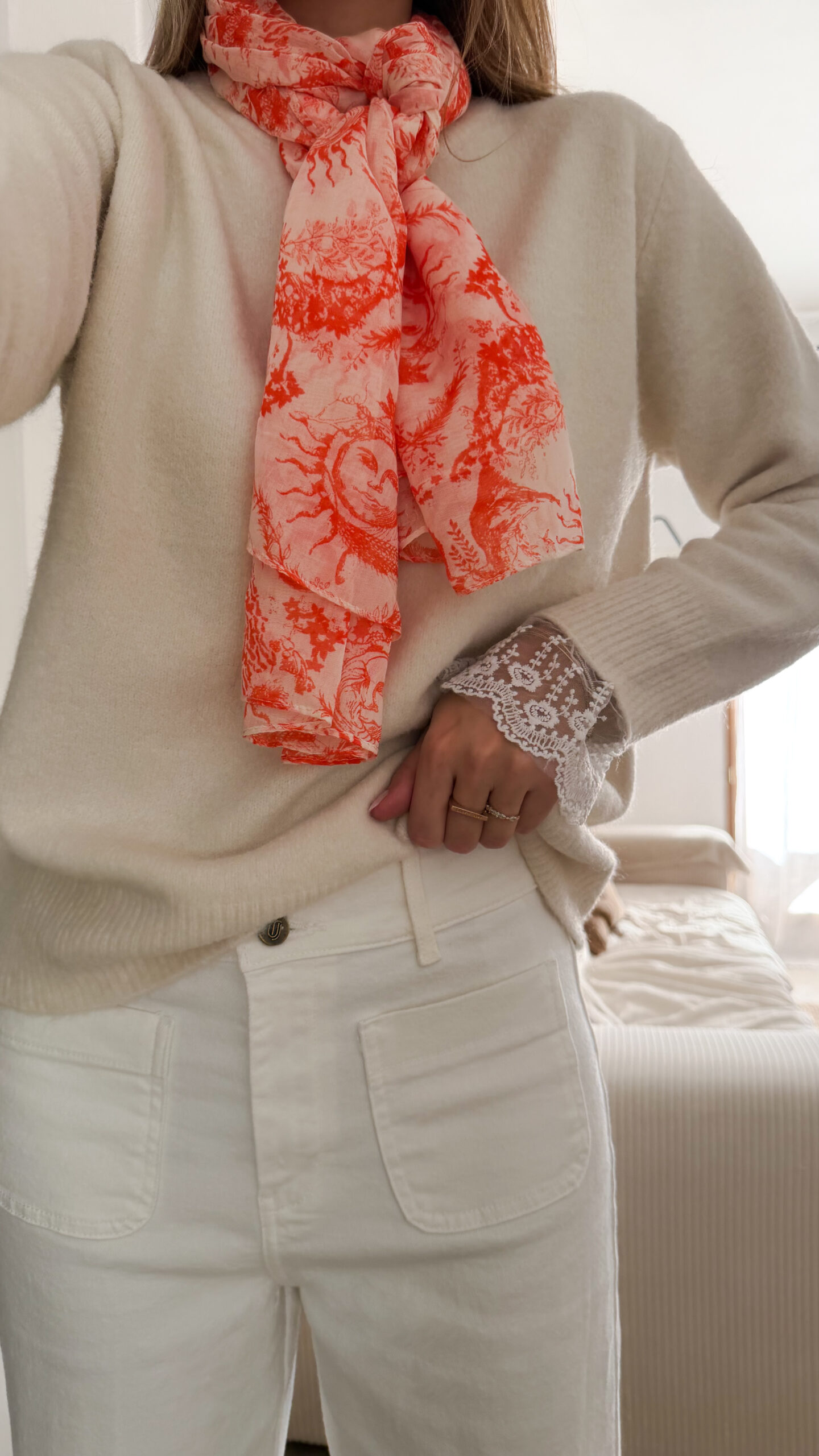 Foulard rose et orange motif Toile de Jouy porté avec pull beige et pantalon blanc