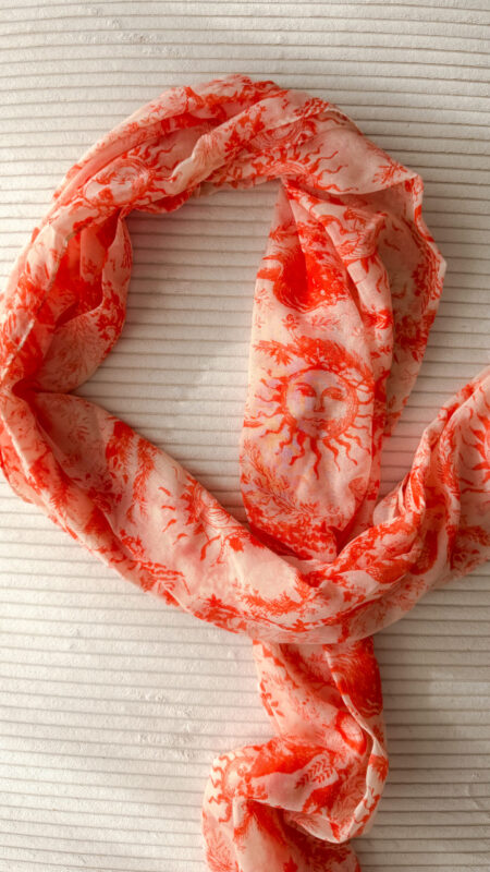 Foulard rose et orange motif Toile de Jouy porté avec pull beige et pantalon blanc