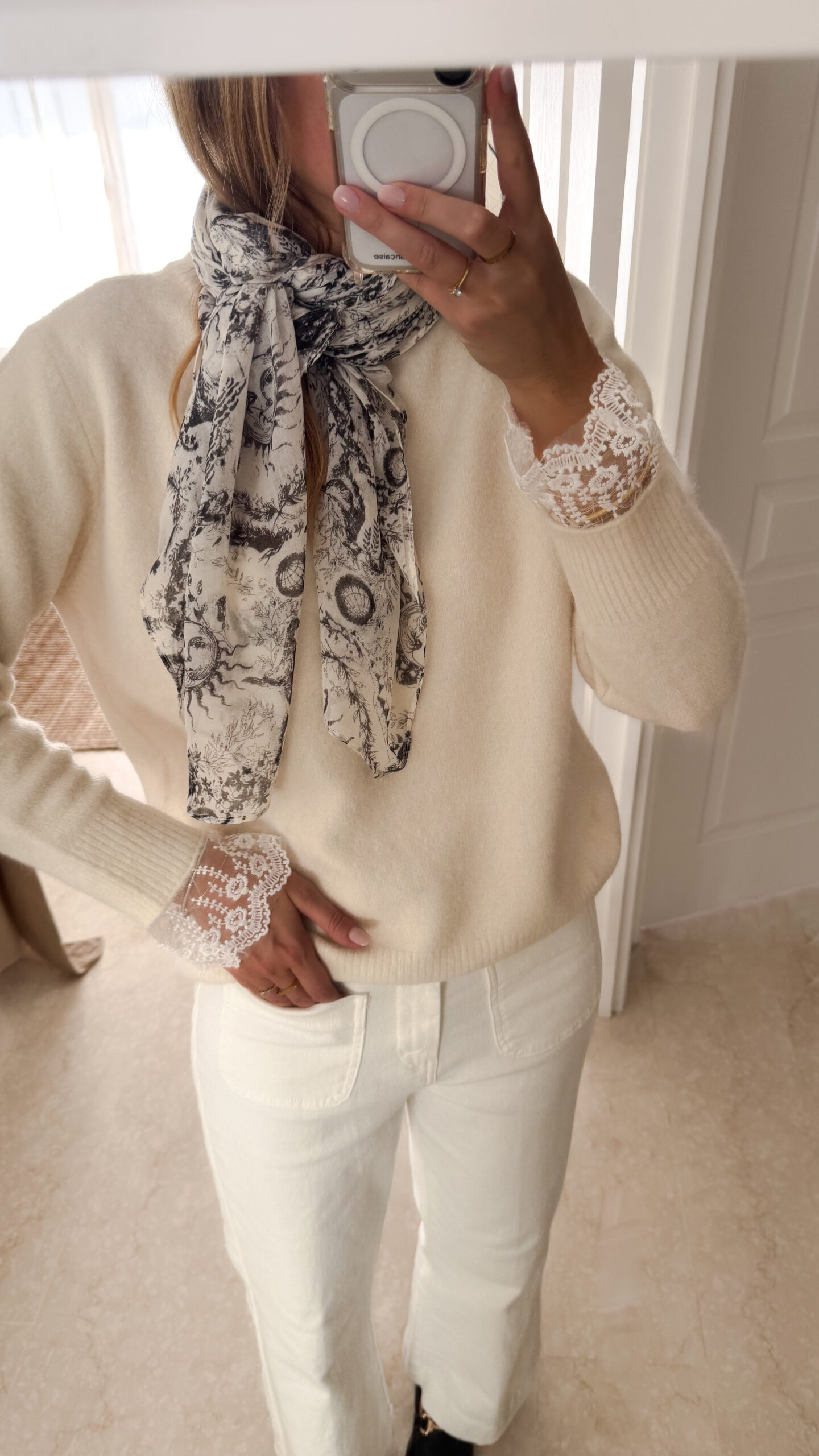 Foulard blanc et noir à imprimé artistique porté autour du cou avec un pull écru.