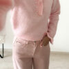 Pull rose doux à col volanté avec boutons perles porté avec un pantalon rose coupe droite.