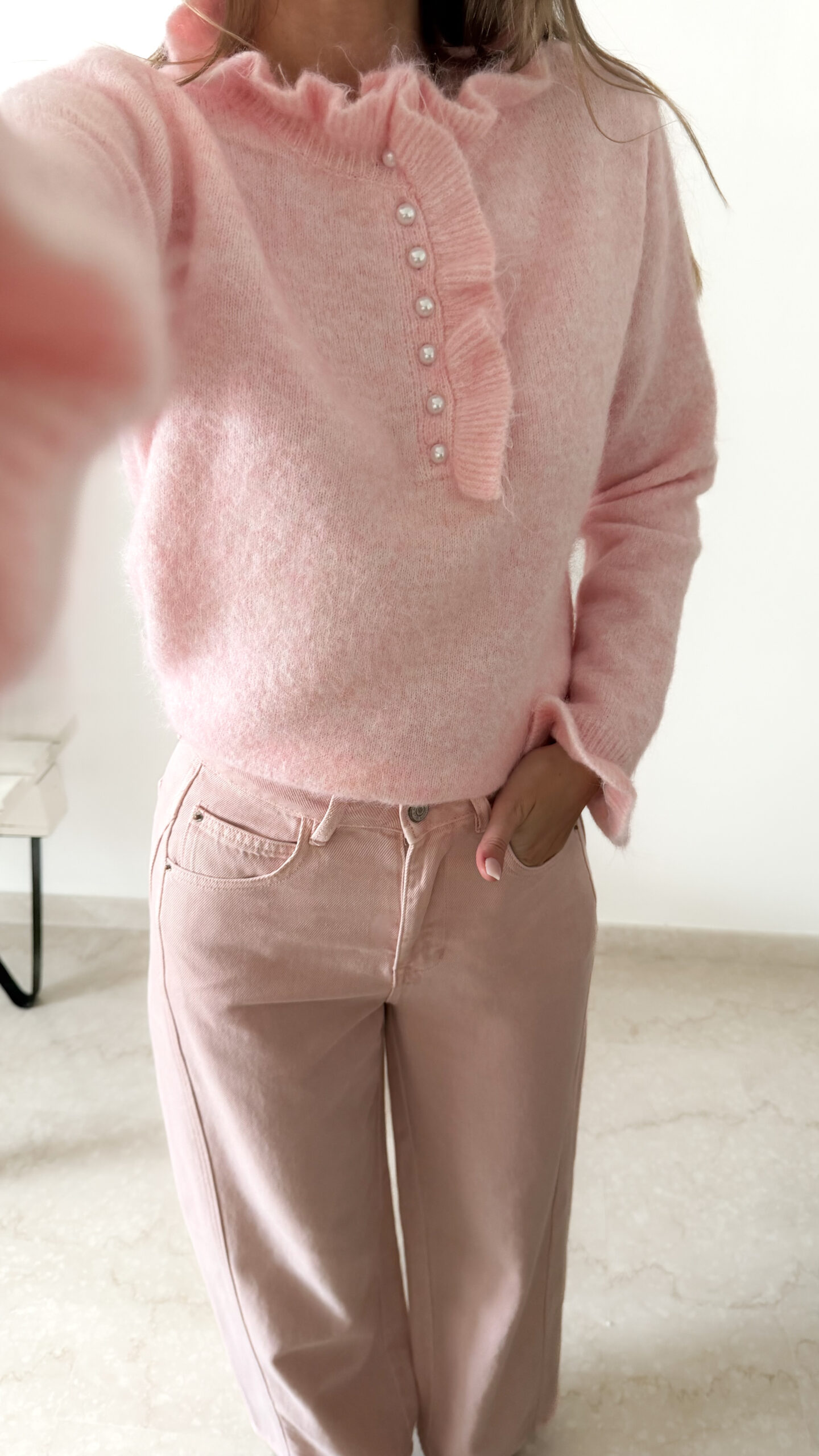 Pull rose doux à col volanté avec boutons perles porté avec un pantalon rose coupe droite.