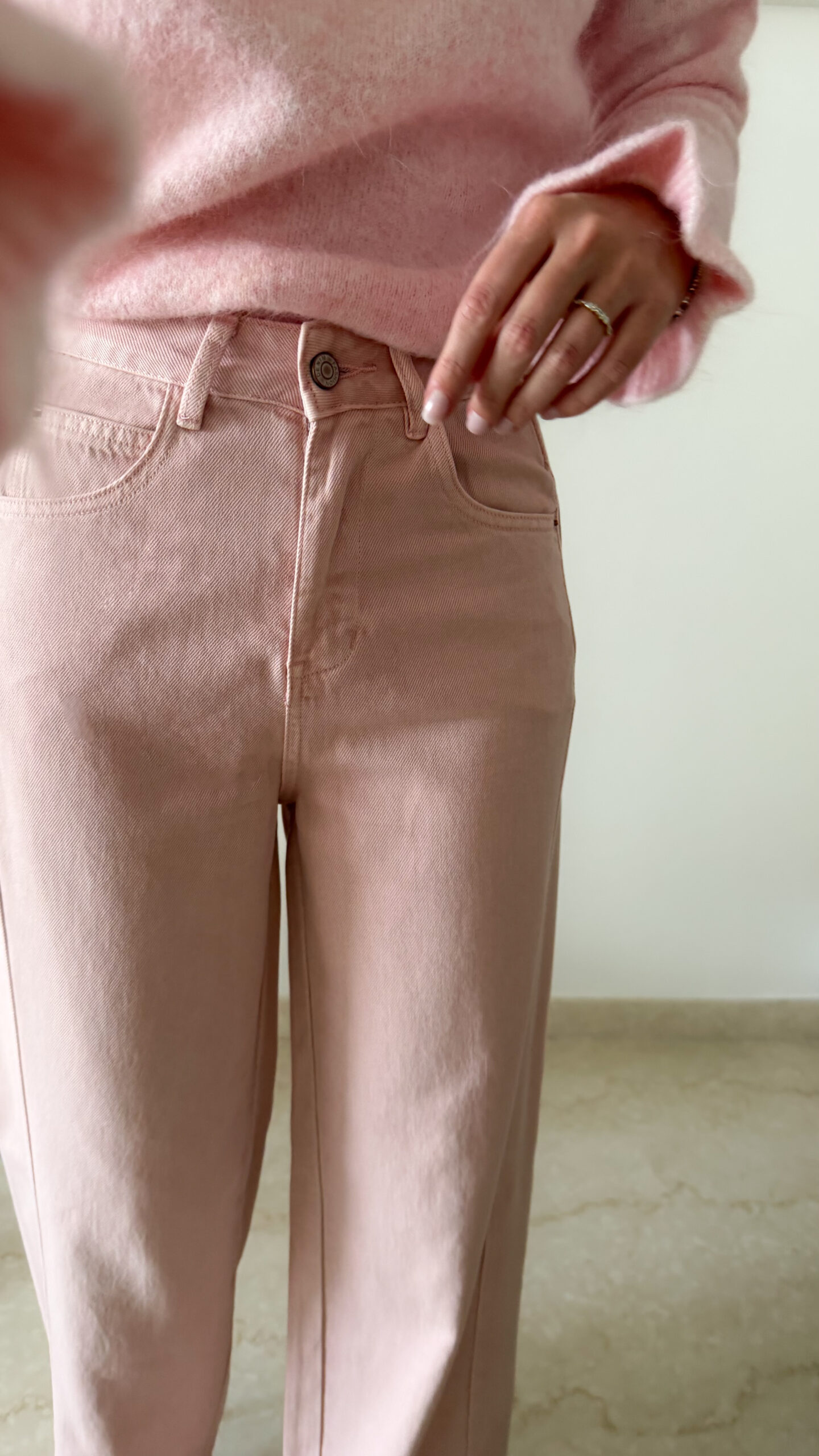 Pull rose doux à col volanté avec boutons perles porté avec un pantalon rose coupe droite.