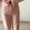Pull rose doux à col volanté avec boutons perles porté avec un pantalon rose coupe droite.
