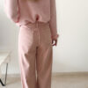 Pull rose doux à col volanté avec boutons perles porté avec un pantalon rose coupe droite.
