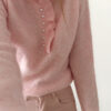 Pull rose doux à col volanté avec boutons perles porté avec un pantalon rose coupe droite.