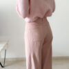 Pull rose doux à col volanté avec boutons perles porté avec un pantalon rose coupe droite.
