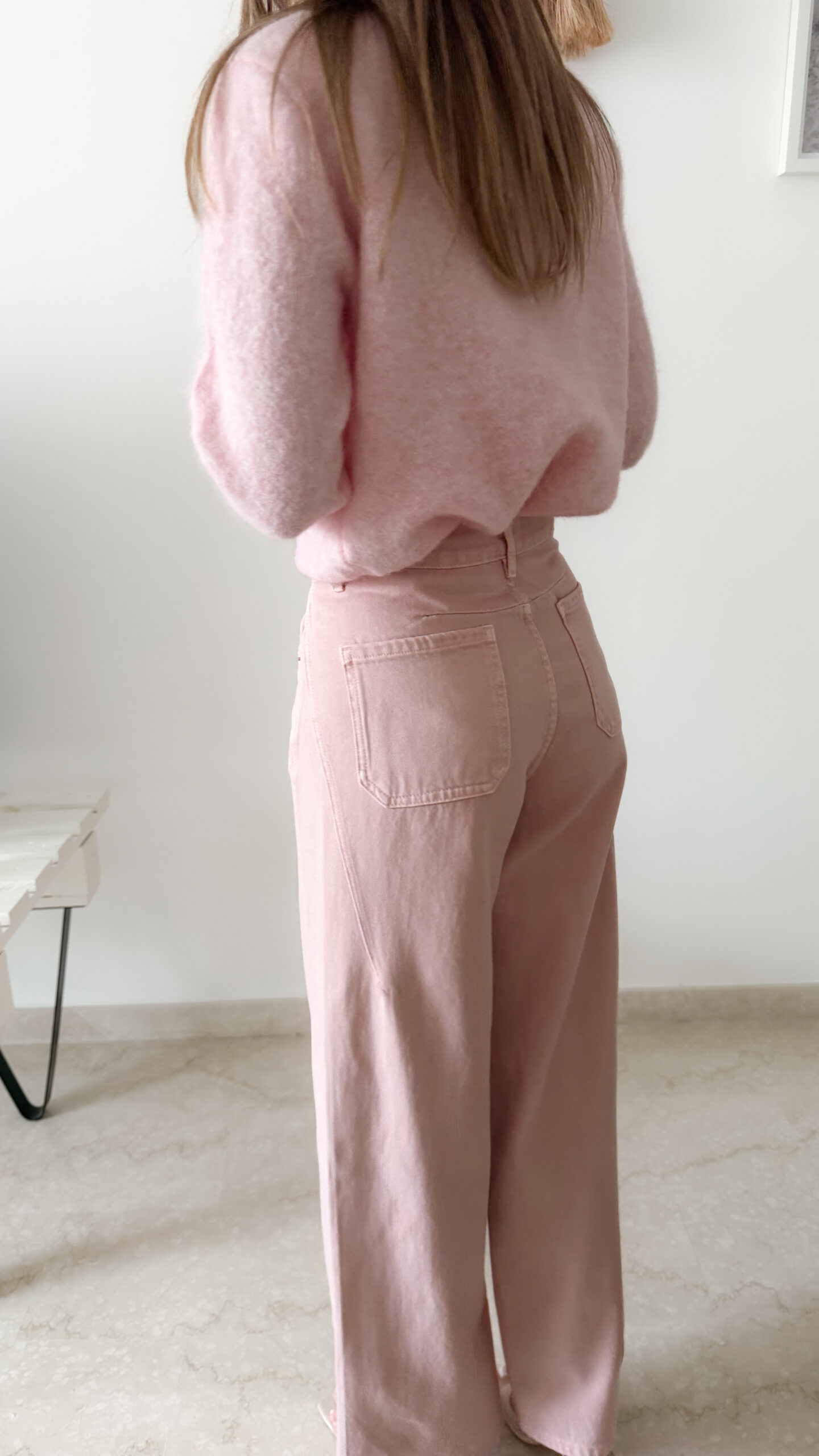 Pull rose doux à col volanté avec boutons perles porté avec un pantalon rose coupe droite.