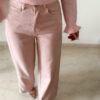 Pull rose doux à col volanté avec boutons perles porté avec un pantalon rose coupe droite.