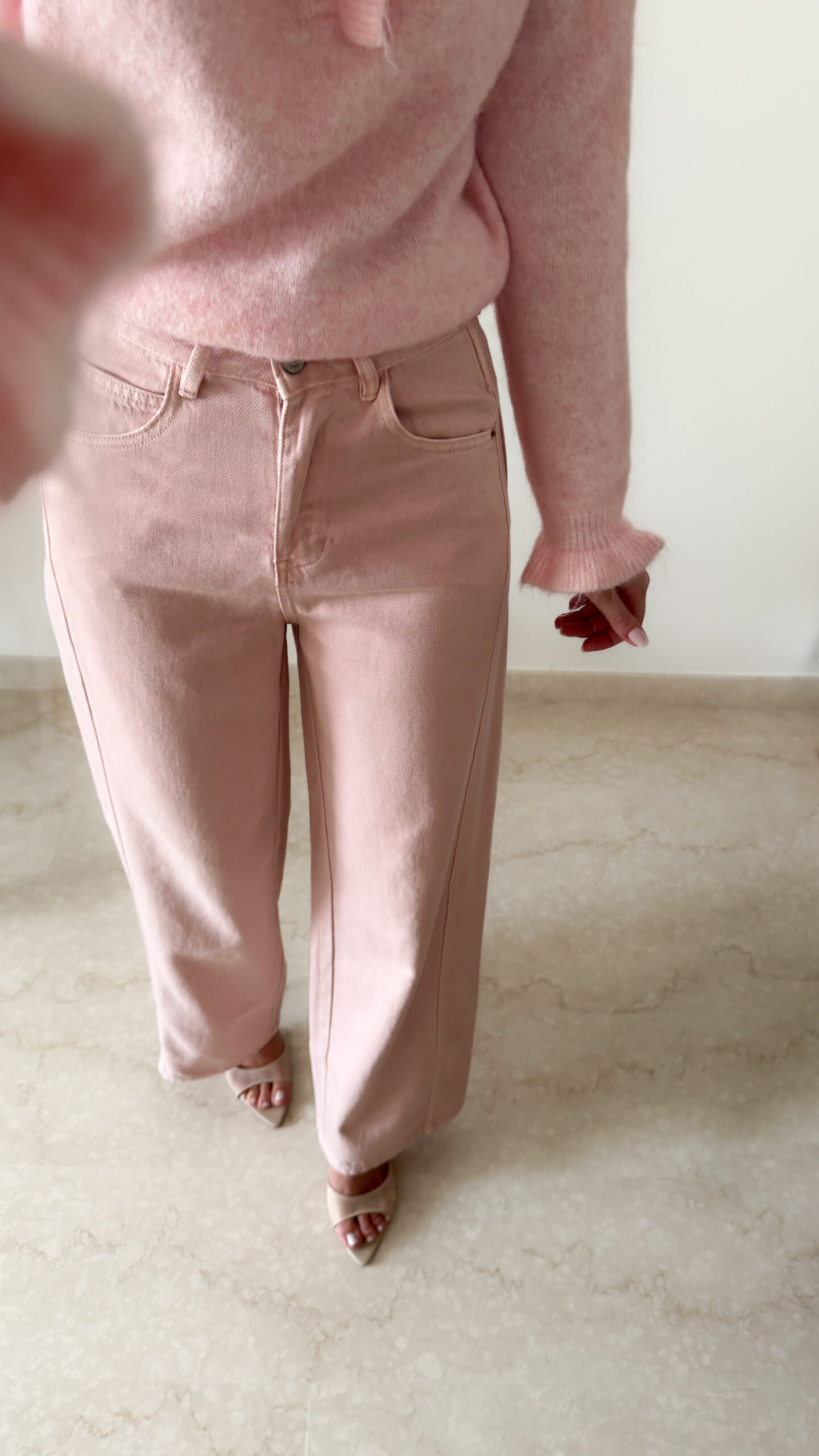 Pull rose doux à col volanté avec boutons perles porté avec un pantalon rose coupe droite.