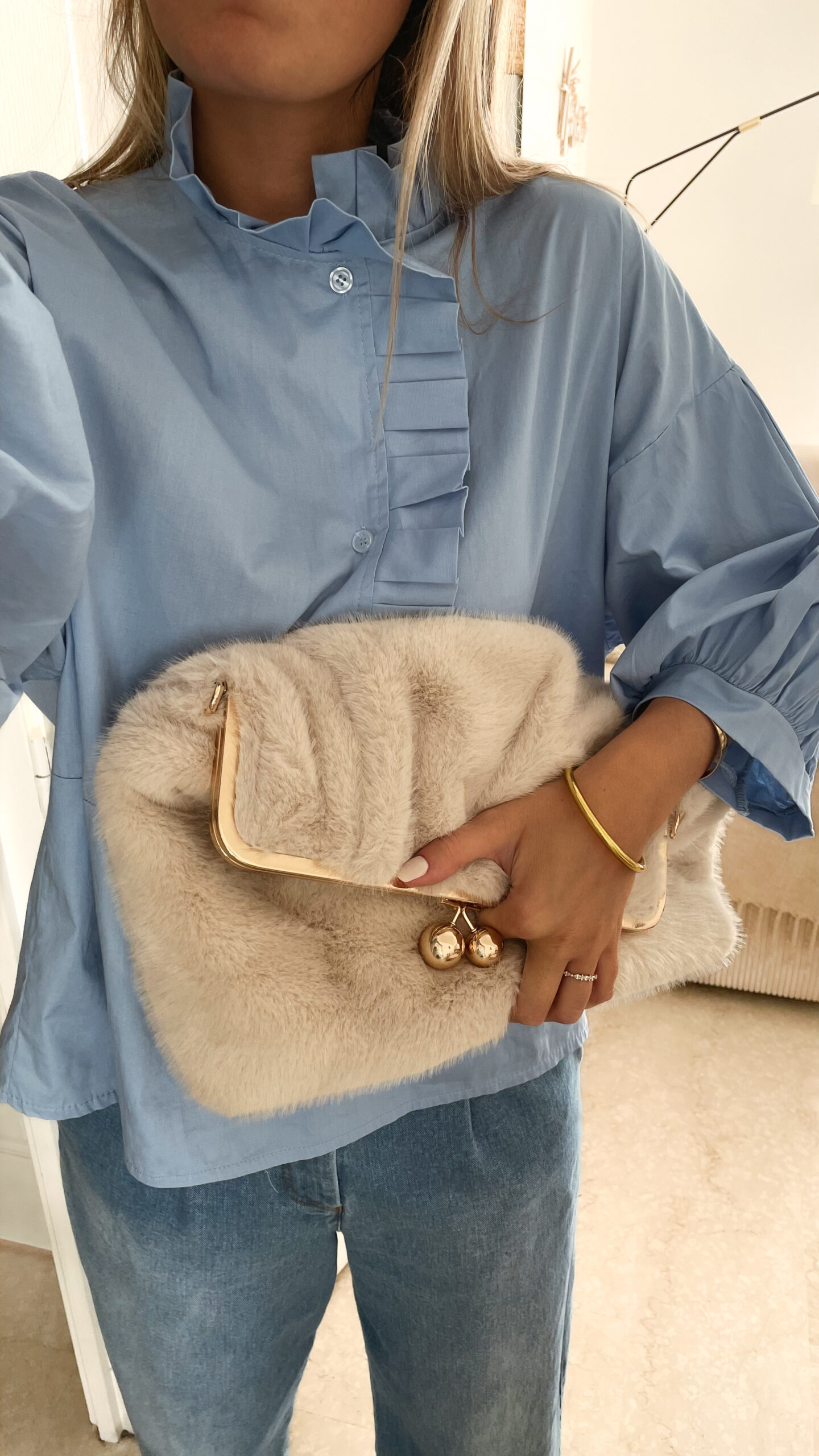 Vetement de femme avec la blouse Celine bleue volantée, le sac fourrure ecru bourse et le jean gabriel bleu clair