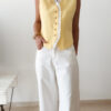 Gilet sans manches à boutons avec finition dentelle, une pièce élégante et féminine disponible en rose et jaune.
