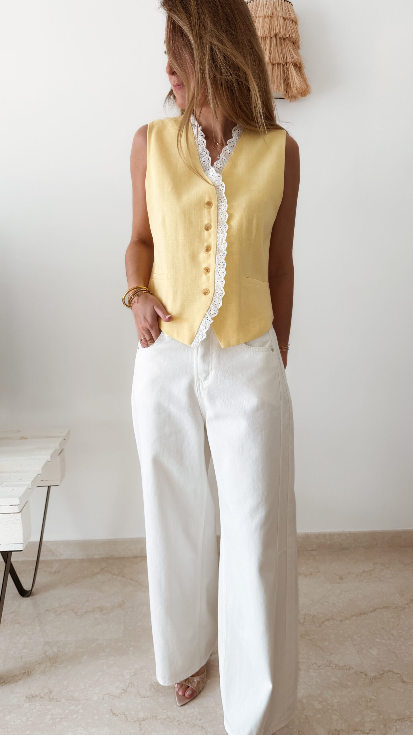 Gilet sans manches à boutons avec finition dentelle, une pièce élégante et féminine disponible en rose et jaune.