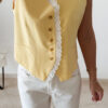 Gilet sans manches à boutons avec finition dentelle, une pièce élégante et féminine disponible en rose et jaune.