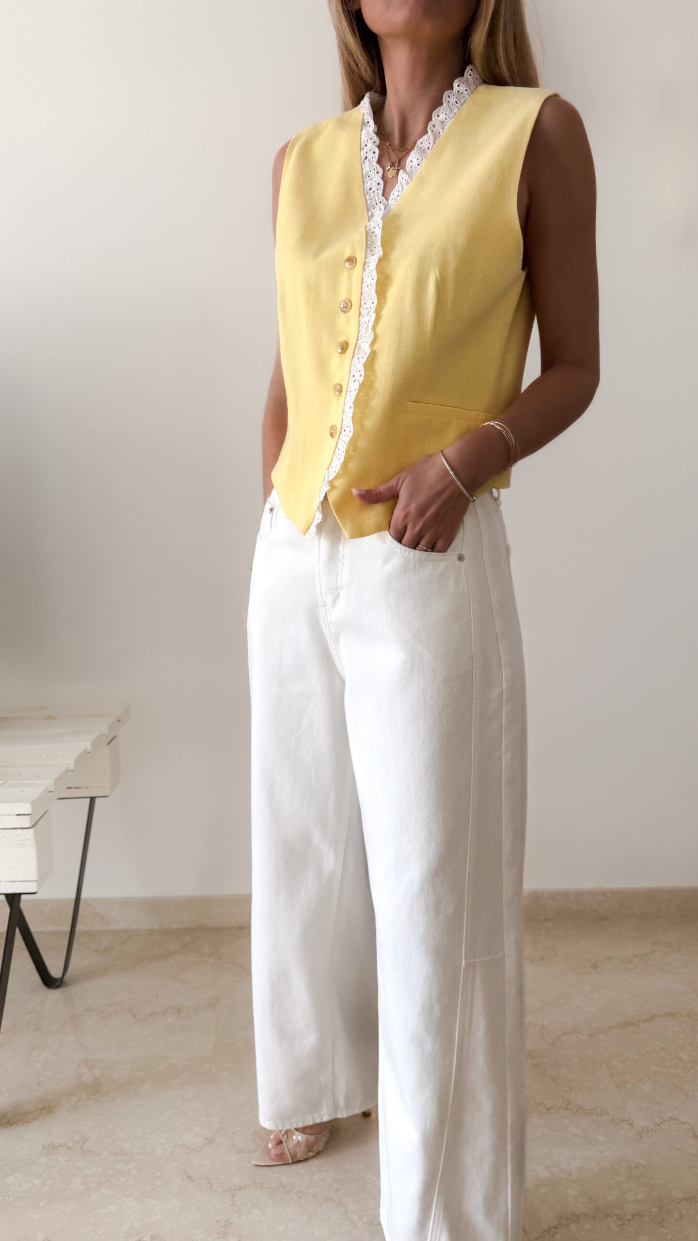 Gilet sans manches à boutons avec finition dentelle, une pièce élégante et féminine disponible en rose et jaune.