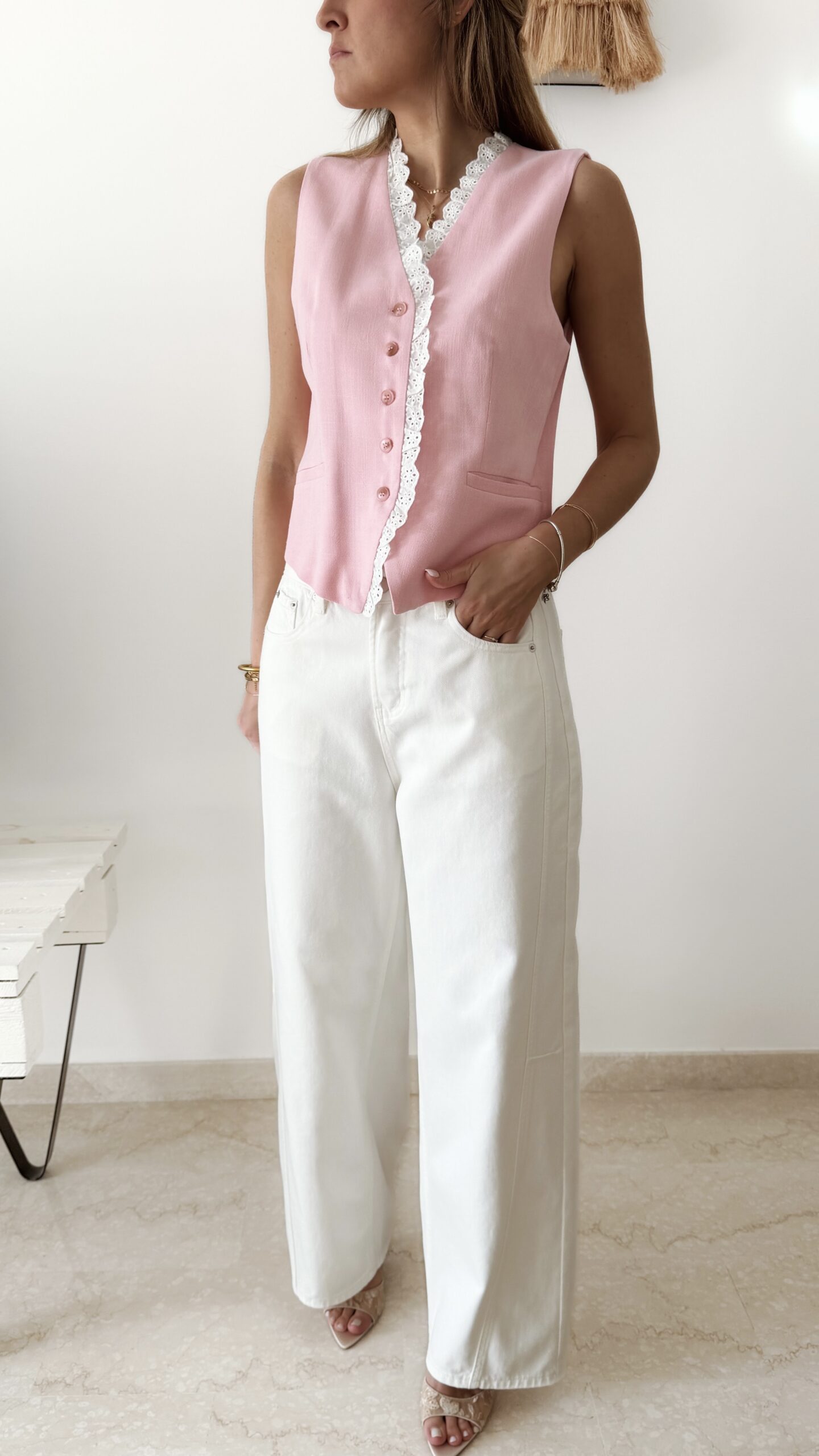 Gilet sans manches à boutons avec finition dentelle, une pièce élégante et féminine disponible en rose et jaune.