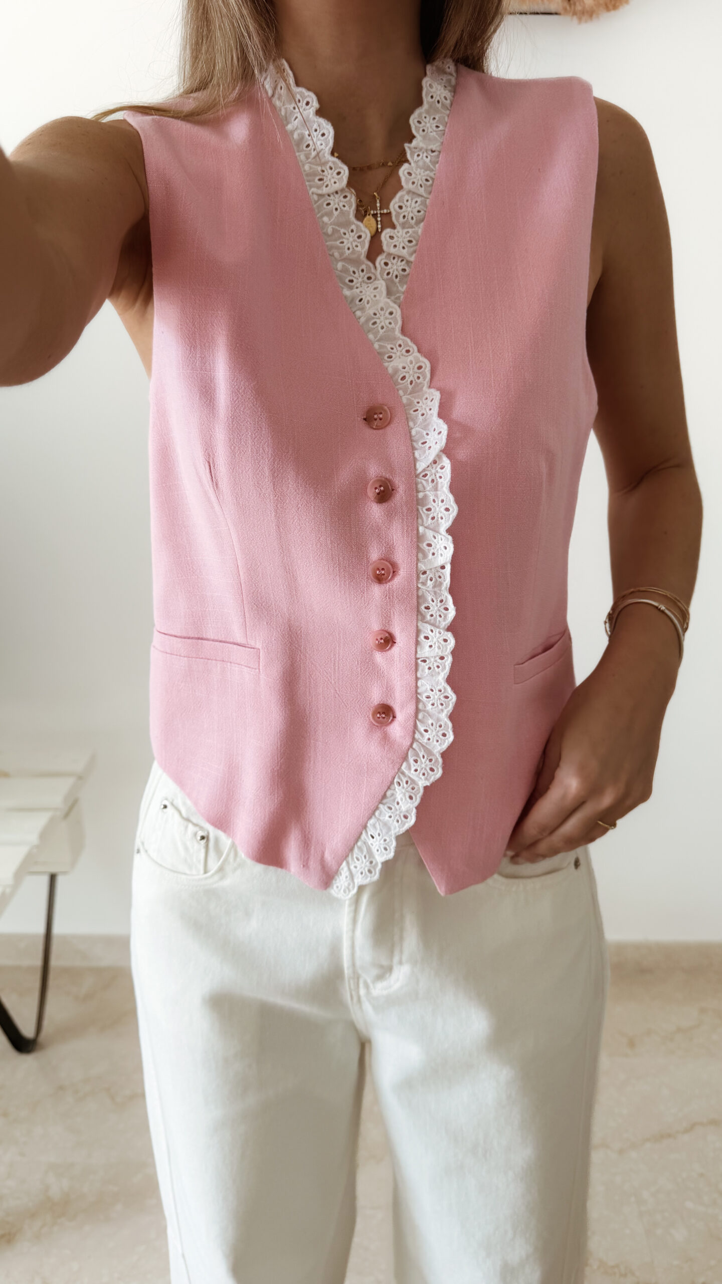 Gilet sans manches à boutons avec finition dentelle, une pièce élégante et féminine disponible en rose et jaune.