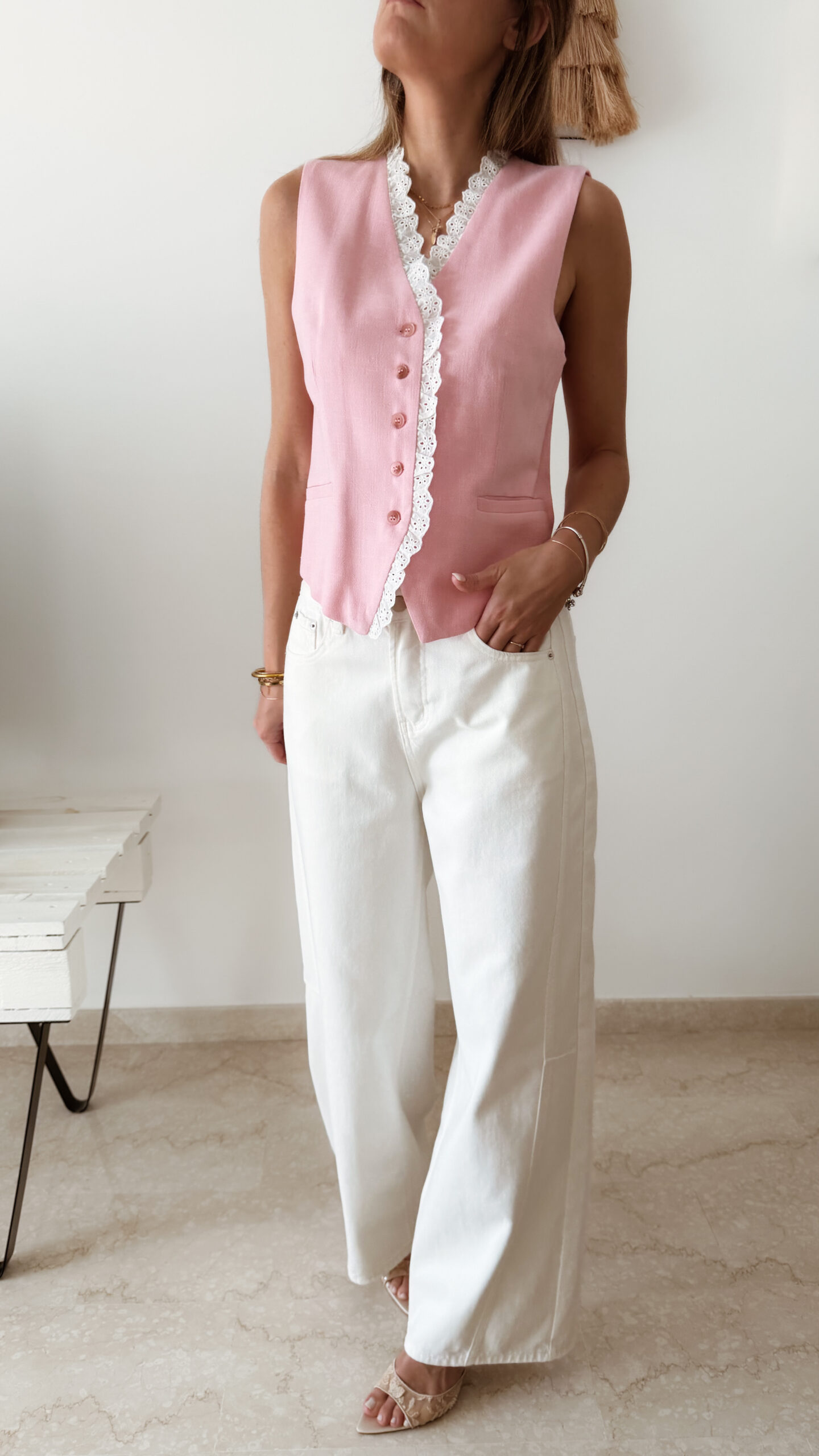 Gilet sans manches à boutons avec finition dentelle, une pièce élégante et féminine disponible en rose et jaune.