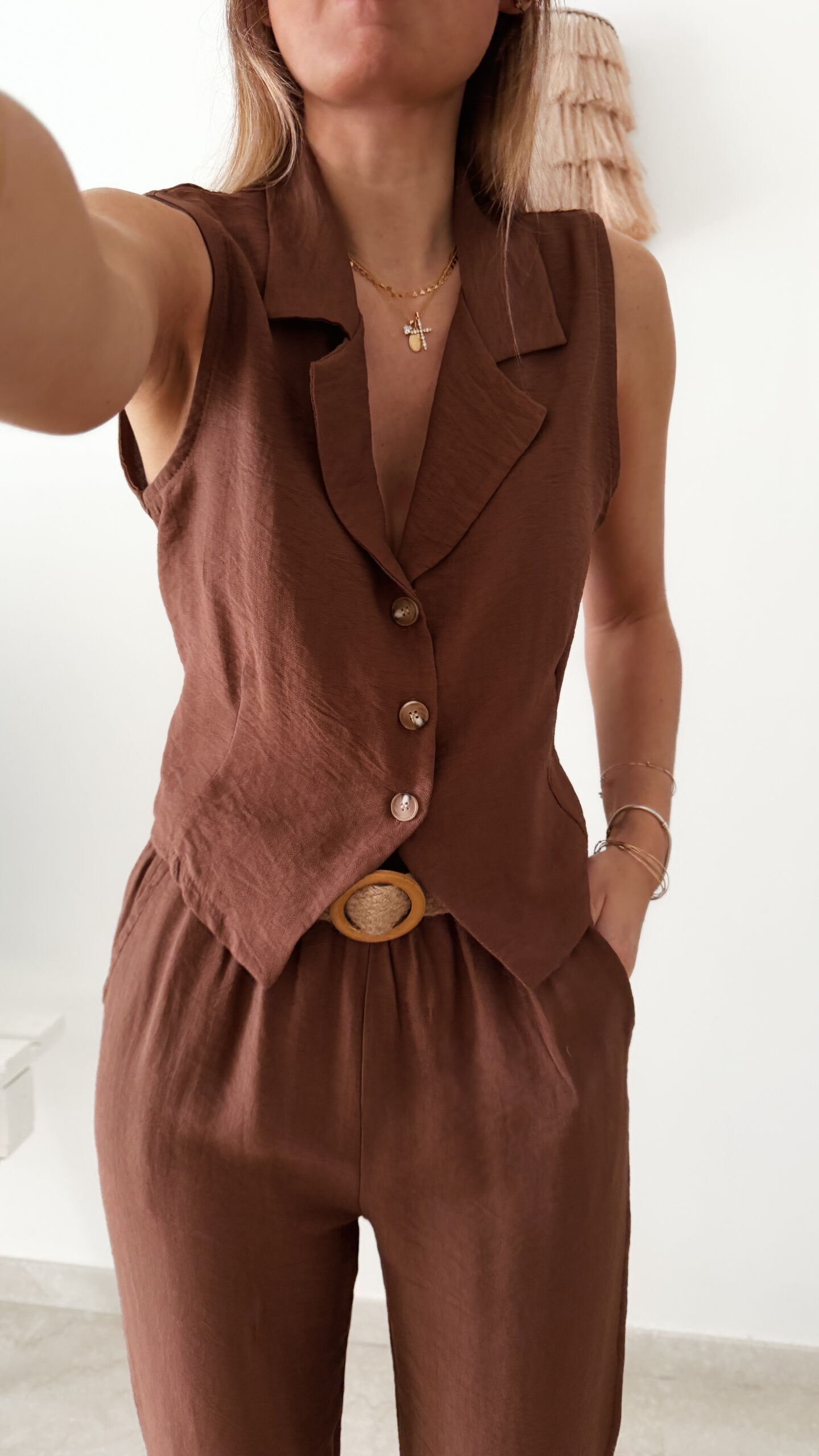 Femme portant un ensemble marron composé d’un gilet sans manches boutonné et d’un pantalon fluide taille haute.
