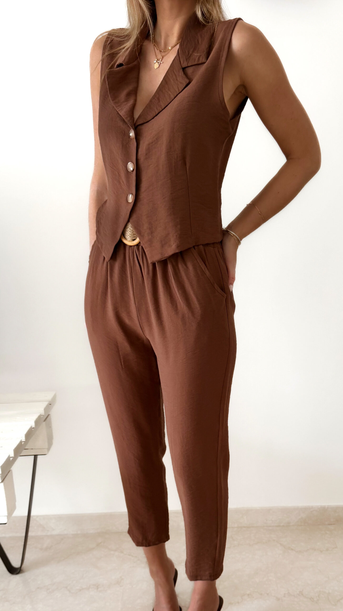Femme portant un ensemble marron composé d’un gilet sans manches boutonné et d’un pantalon fluide taille haute.