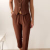 Femme portant un ensemble marron composé d’un gilet sans manches boutonné et d’un pantalon fluide taille haute.