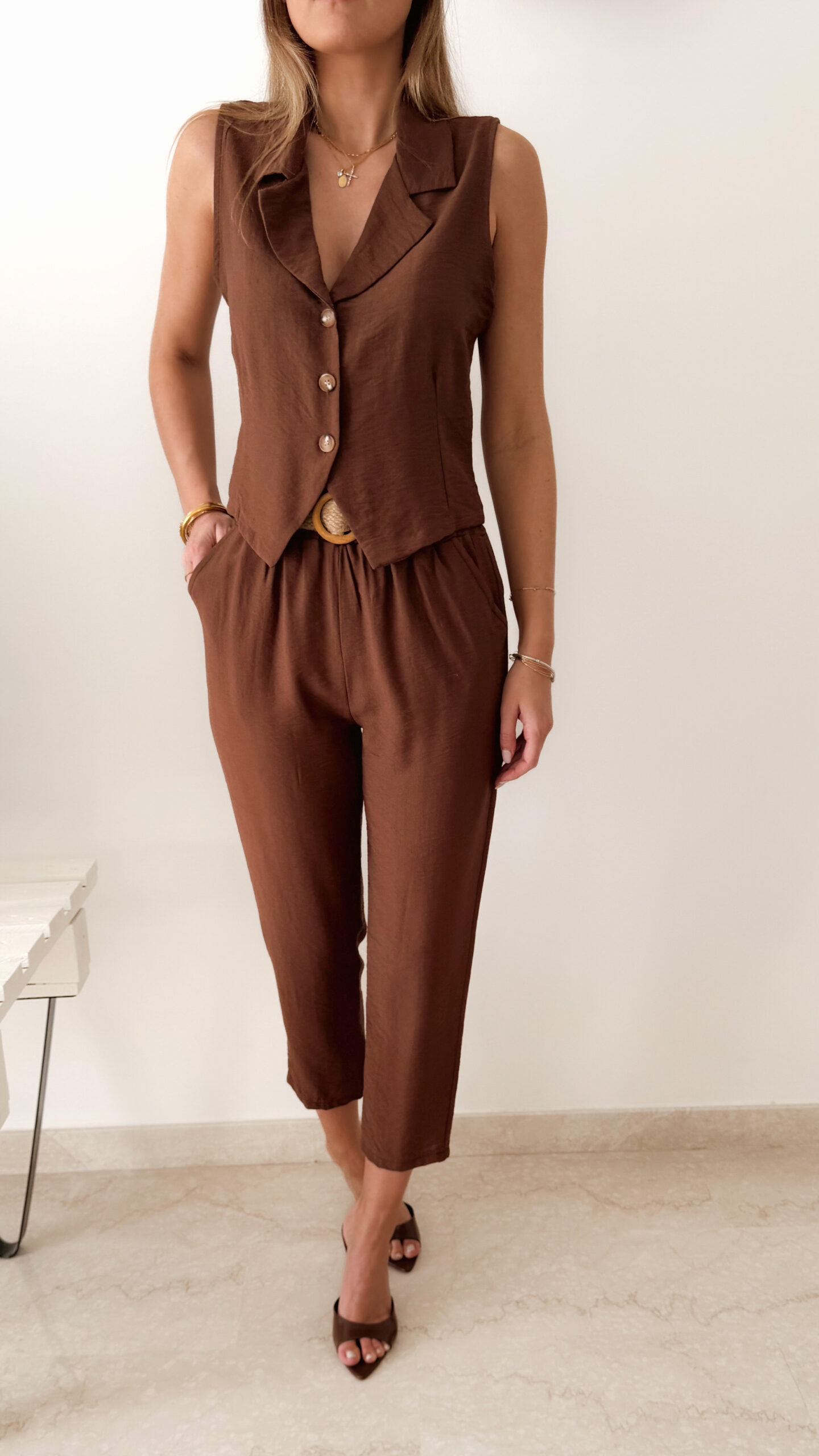 Femme portant un ensemble marron composé d’un gilet sans manches boutonné et d’un pantalon fluide taille haute.