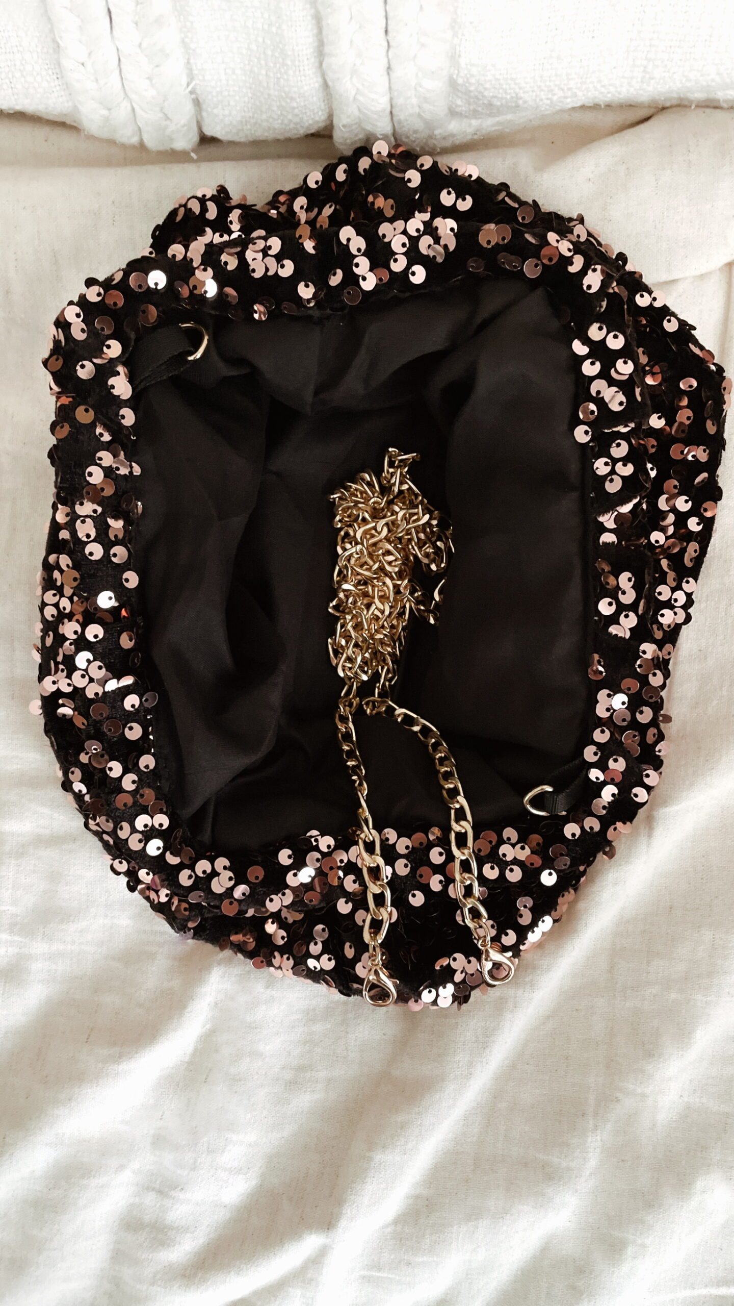 Femme tenant un sac à sequins chocolat scintillant, assorti à une tenue brune élégante avec chemisier et gilet en laine.