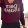 Femme portant un pull bordeaux à inscription “Ciao Amore”, associé à une jupe noire, une écharpe imprimée beige, un sac à franges et des mocassins léopard pour un look automnal chic et décontracté.