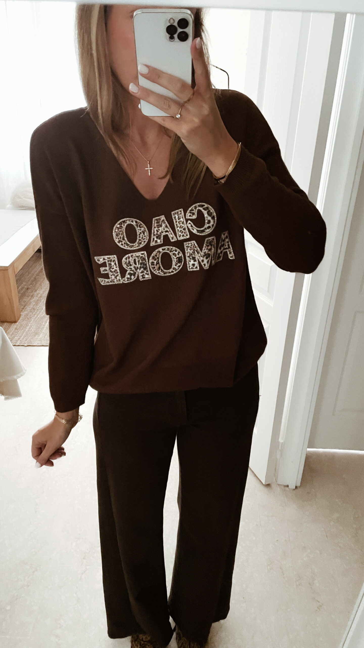 Femme portant un pull chocolat à inscription "Ciao Amore", associé à une écharpe imprimée beige et un pantalon foncé, pour un look automnal chic et décontracté.