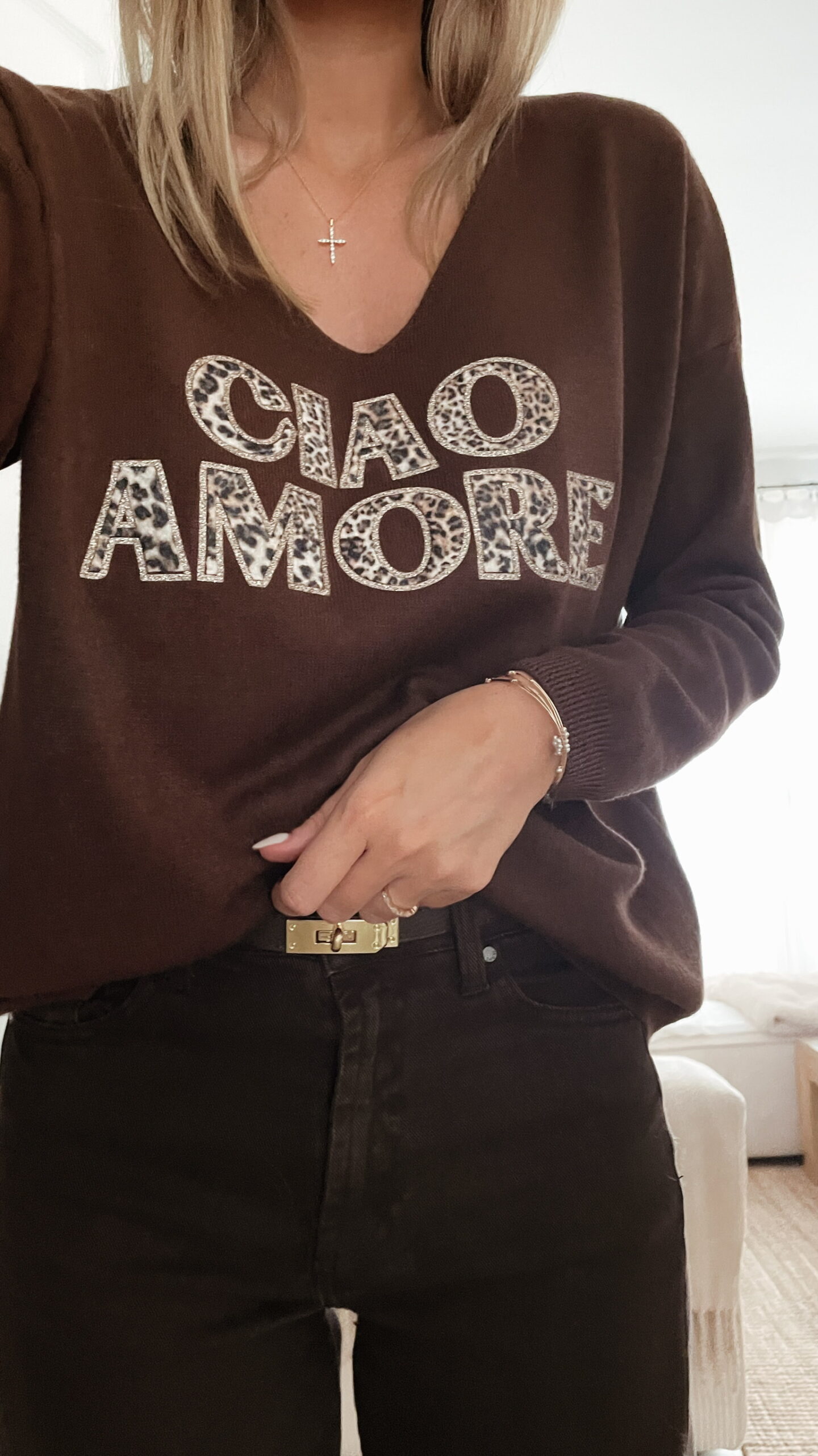Femme portant un pull chocolat à inscription "Ciao Amore", associé à une écharpe imprimée beige et un pantalon foncé, pour un look automnal chic et décontracté.