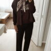 Femme portant un pull chocolat à inscription "Ciao Amore", associé à une écharpe imprimée beige et un pantalon foncé, pour un look automnal chic et décontracté.