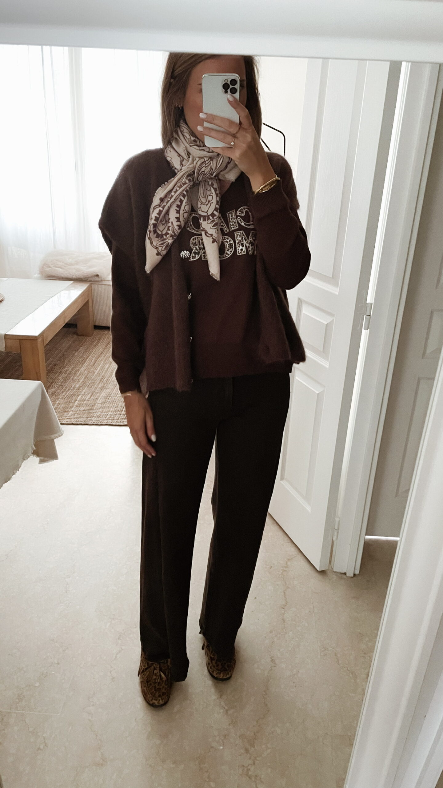 Femme portant un pull chocolat à inscription "Ciao Amore", associé à une écharpe imprimée beige et un pantalon foncé, pour un look automnal chic et décontracté.