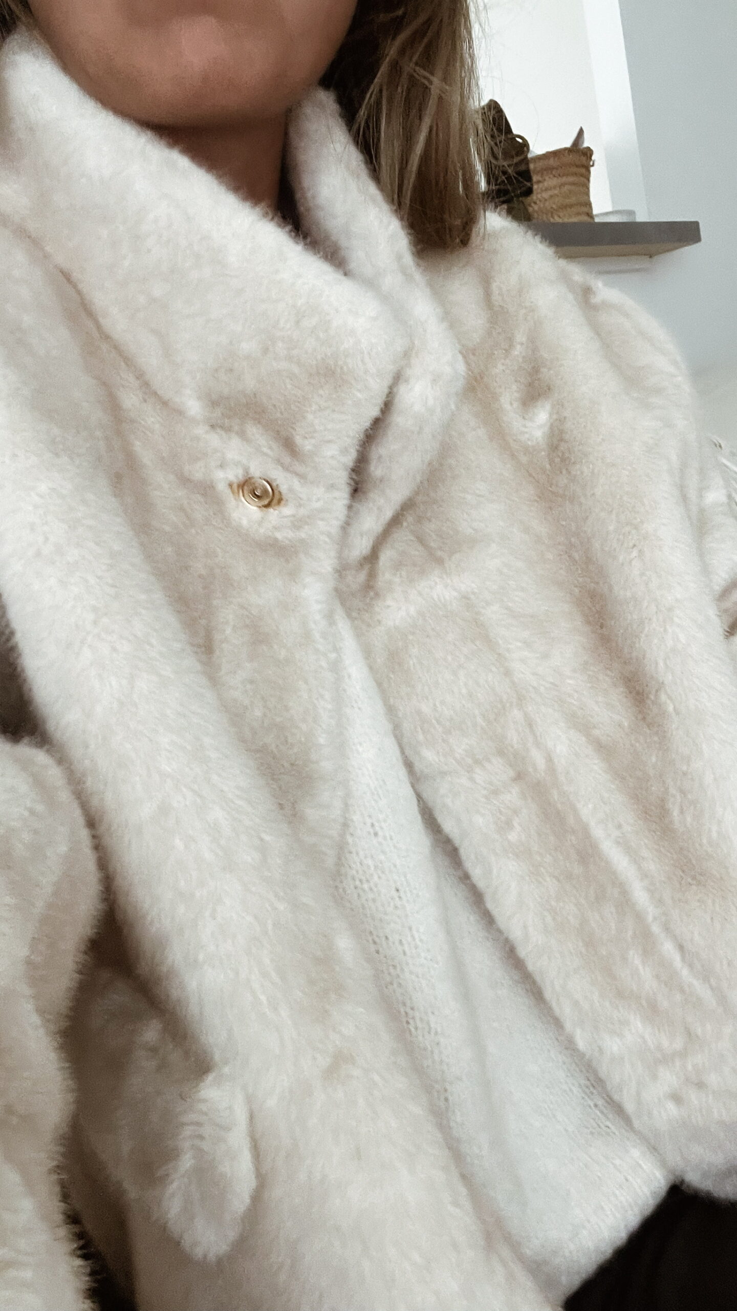 Femme portant une veste en fausse fourrure écrue à col montant, associée à un pantalon foncé et des mocassins imprimés léopard.