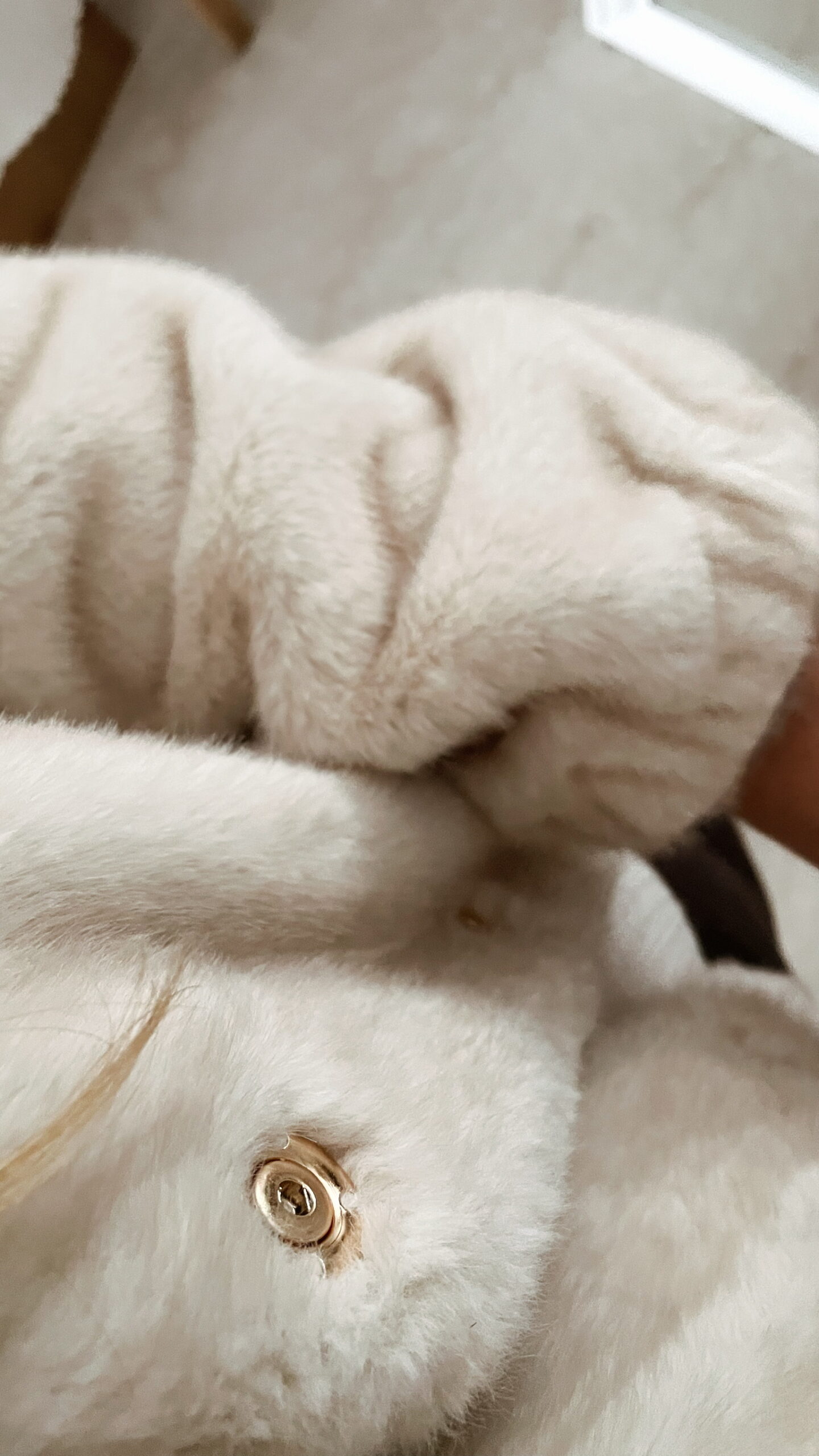 Femme portant une veste en fausse fourrure écrue à col montant, associée à un pantalon foncé et des mocassins imprimés léopard.