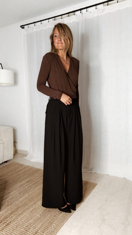 « Femme portant un body marron cache-cœur orné de strass, associé à un pantalon noir élégant »