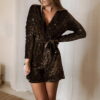 Femme portant une combinaison short à sequins marron avec manches longues et ceinture nouée à la taille.