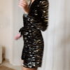 Femme portant une combinaison short à sequins noirs et argentés, manches longues et décolleté croisé.