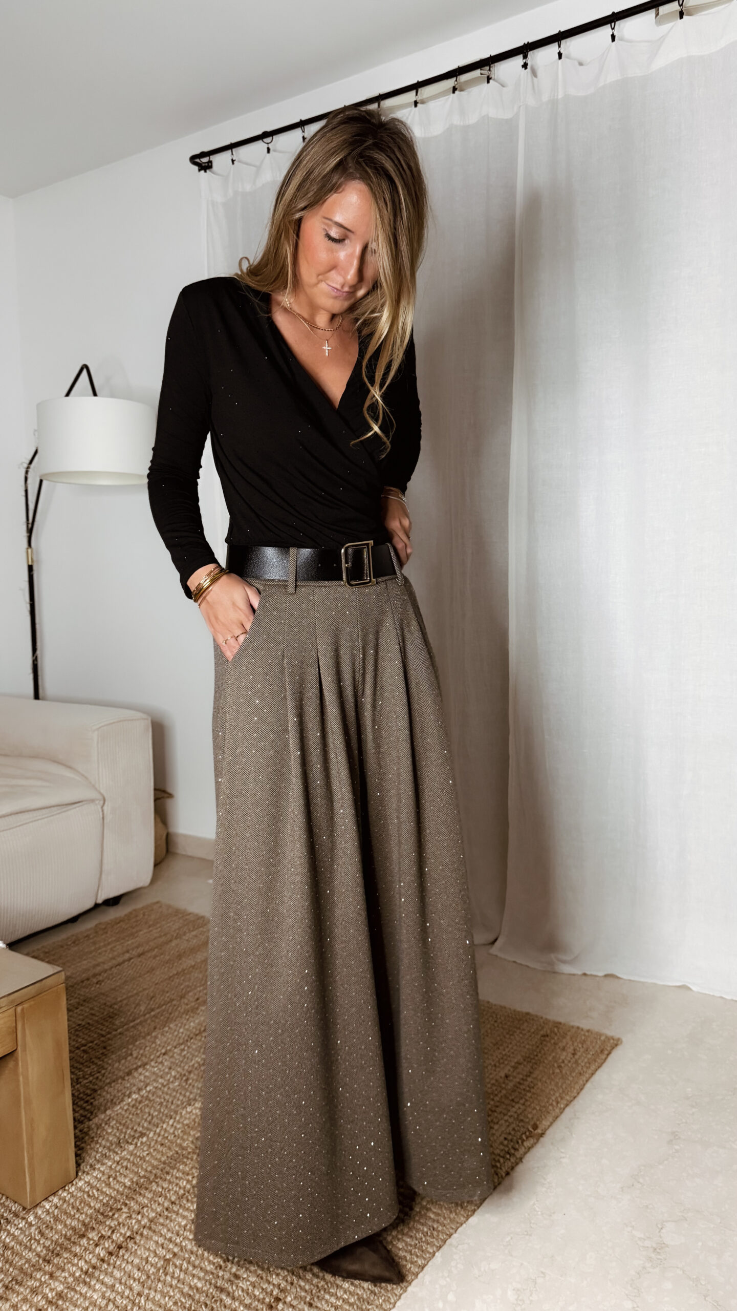 « Femme portant un body noir croisé à strass avec un pantalon large marron à chevrons et détails scintillants, tenue élégante chic. »