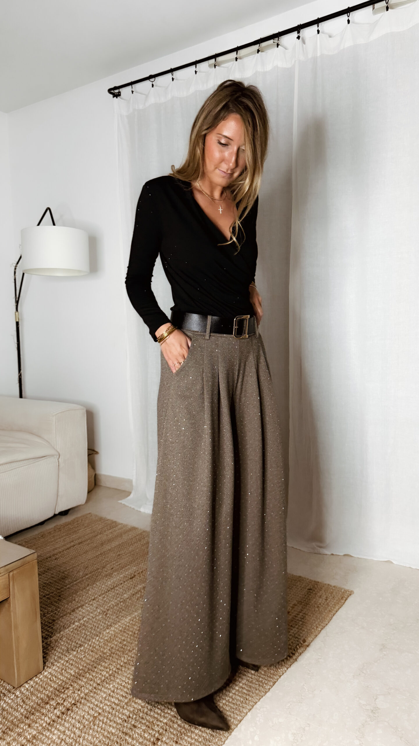« Femme portant un body noir croisé à strass avec un pantalon large marron à chevrons et détails scintillants, tenue élégante chic. »