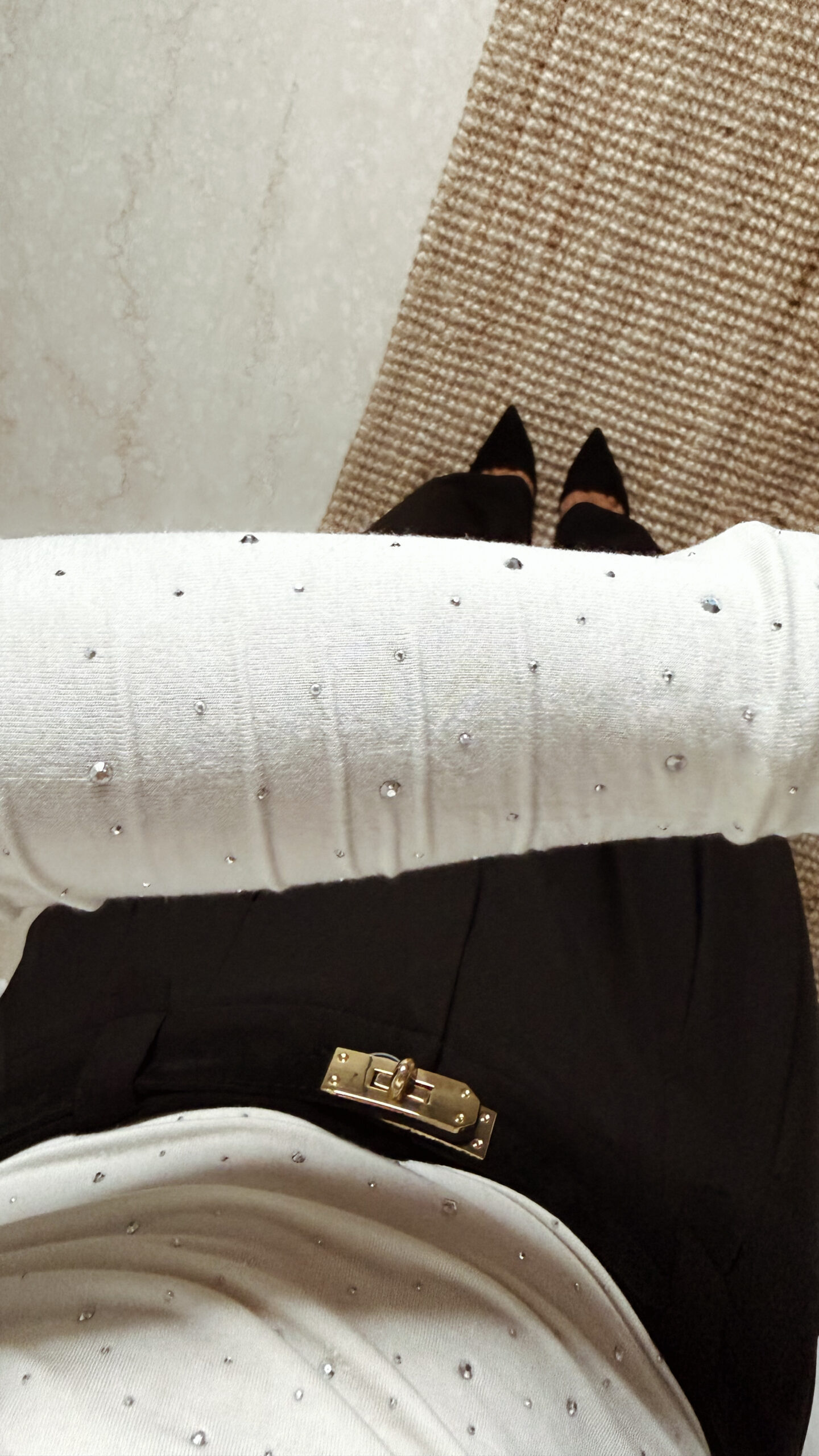 « Femme portant un top écru à col roulé orné de strass, associé à un pantalon noir élégant »