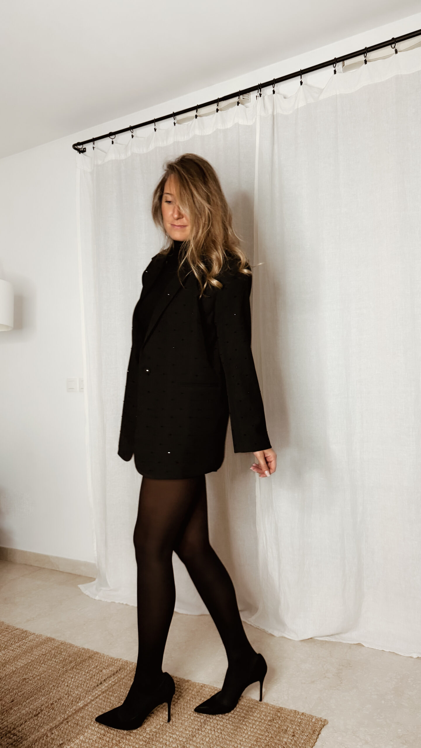 Femme portant un blazer noir à strass avec collants noirs et escarpins, tenue élégante et chic de soirée.
