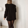 Femme portant un blazer noir à strass avec collants noirs et escarpins, tenue élégante et chic de soirée.