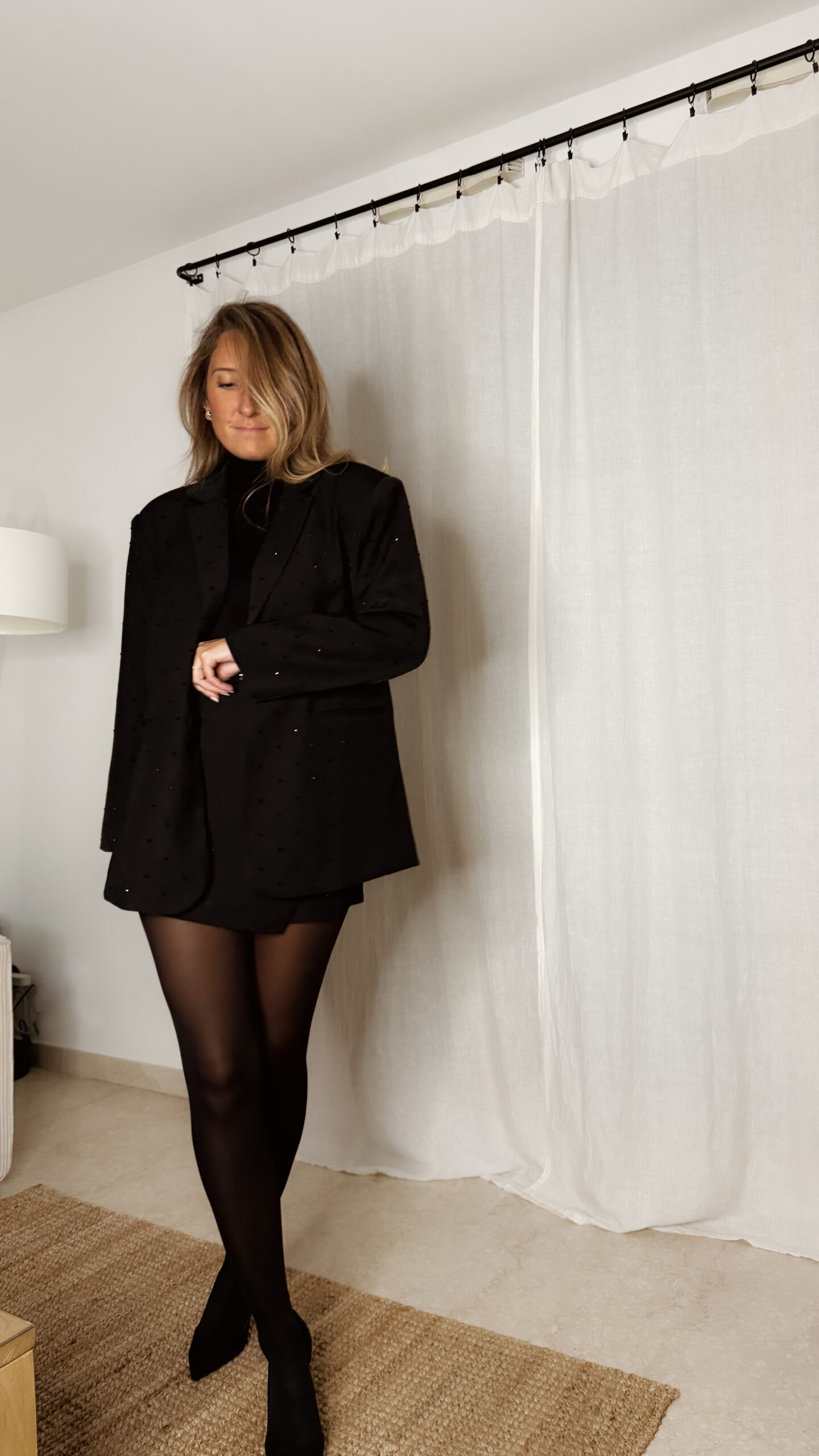 Femme portant un blazer noir à strass avec collants noirs et escarpins, tenue élégante et chic de soirée.