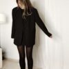 Femme portant un blazer noir à strass avec collants noirs et escarpins, tenue élégante et chic de soirée.